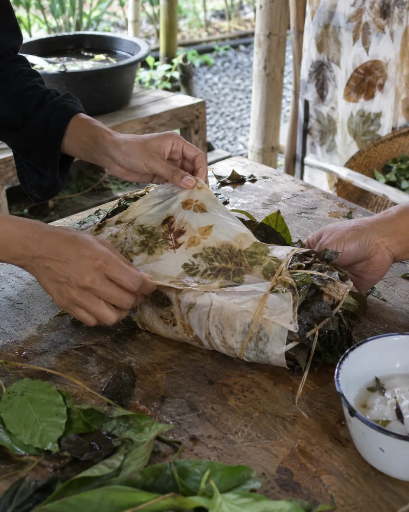 Hands unwrapping naturally leaf-printed cloth during an eco-printing workshop