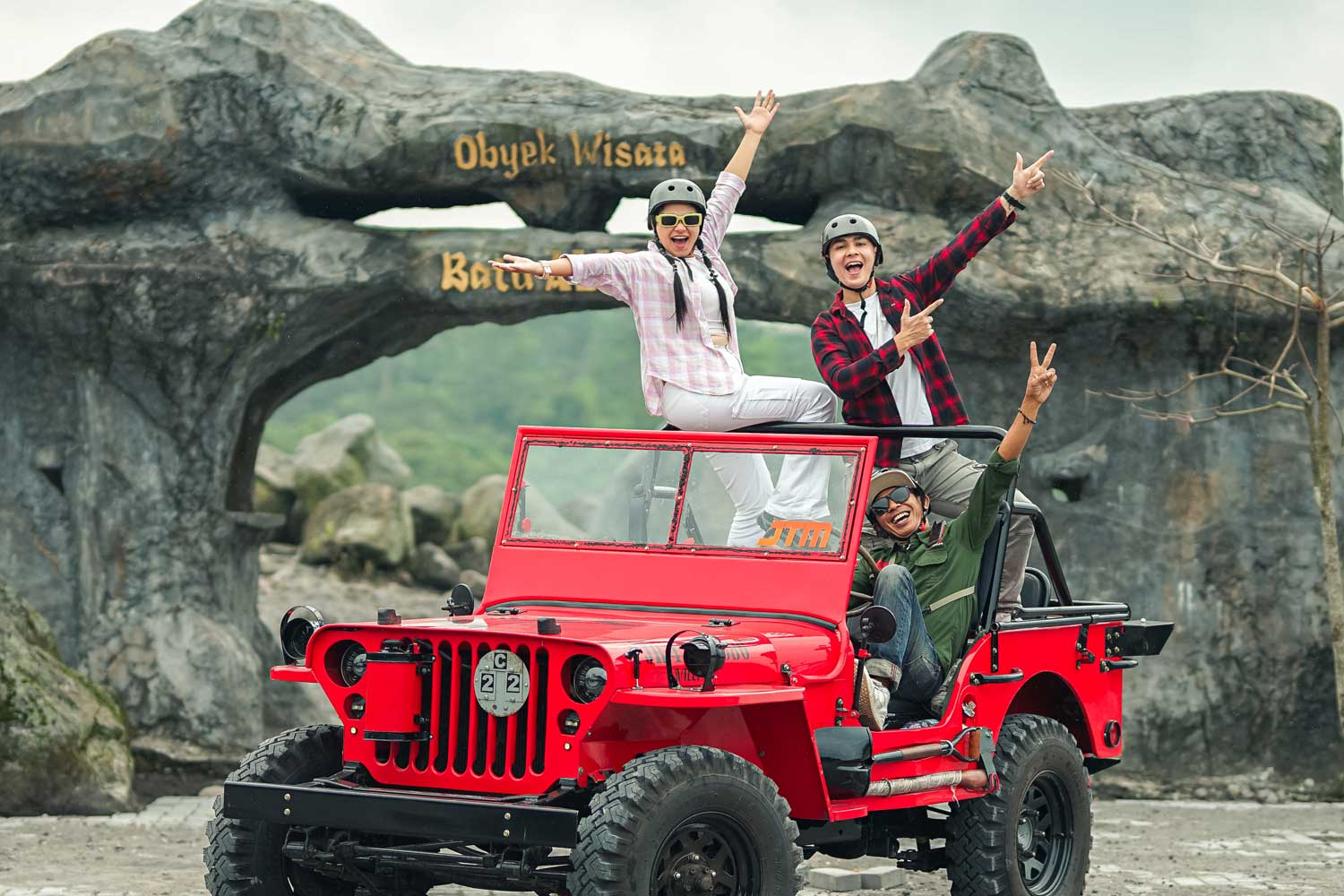 Group posing in a red jeep.